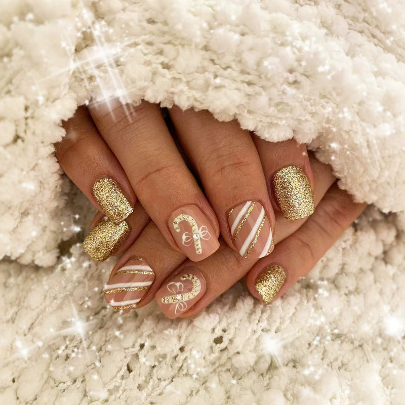 Nude gold glitter Christmas press-on nails with hand-painted candy cane, bow, and stripe designs, short oval nails with a festive atmosphere
