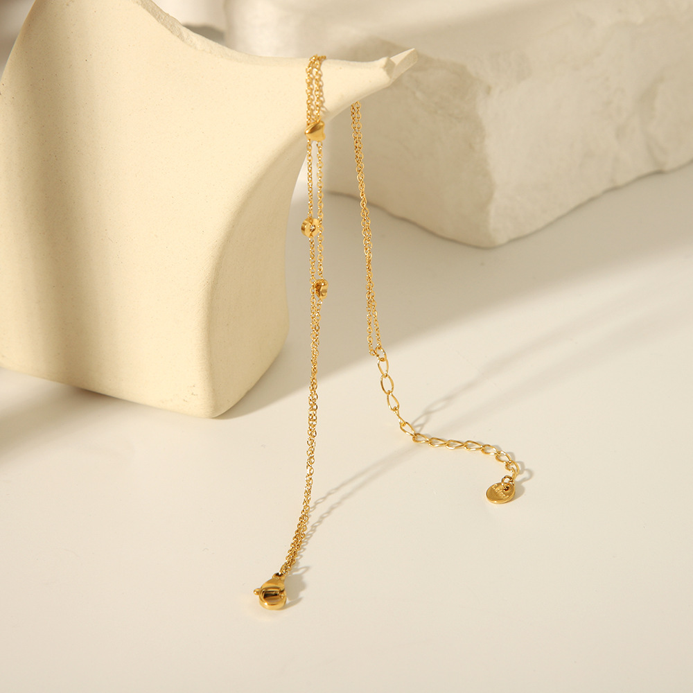 Estilo francés acero de titanio horno de 18K galvanoplastia de oro real doble amor circón tobillera verano femenino todo fósforo joyería de playa