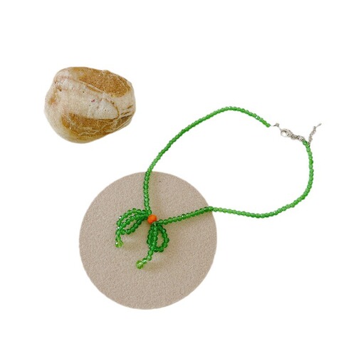 A minimalist and stylish green butterfly knot necklace for women, featuring small, fresh and elegant glass crystal beads, designed as a choker or lockchain.