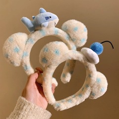 かわいいサメの波点熊のぬいぐるみの髪のカチューシャの女性の誕生日の遊園地の写真を撮って顔を洗って化粧します。