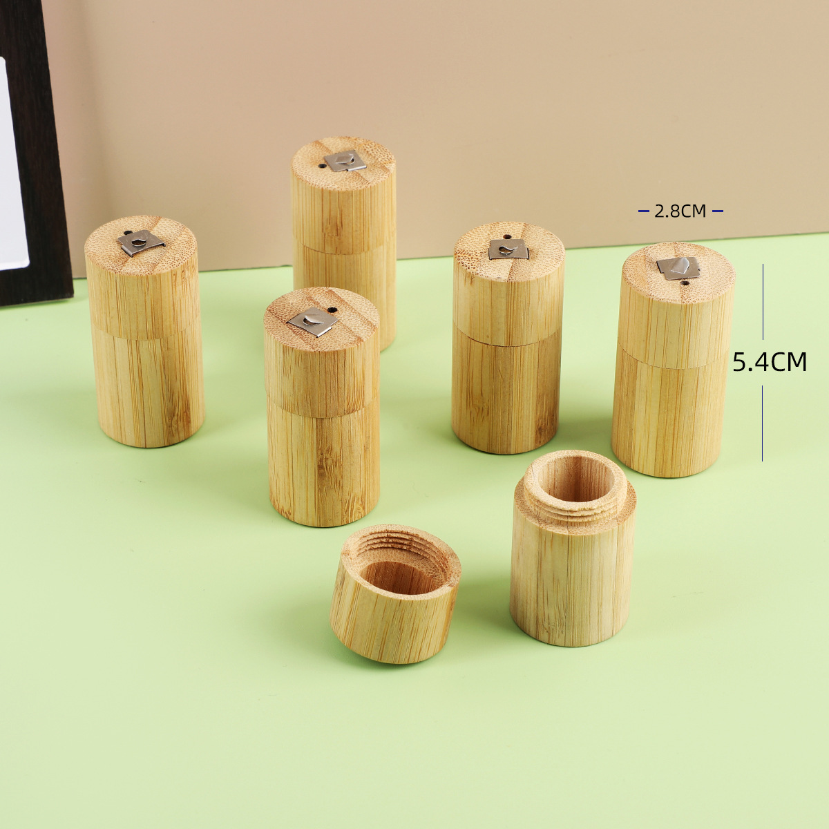 Light brown bamboo cylindrical portable biodegradable floss tube with metallic clasp lid.