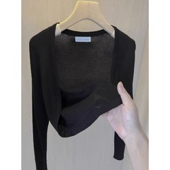 黒の短いアイスニットカーディガンの女性とサスペンダーのスカートの外に春の日焼け止めの薄いコートの小さいショールの上着があります。
