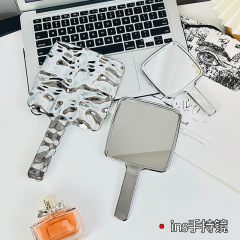 小さな鏡を持ってレトロなins風化粧鏡を持っています。