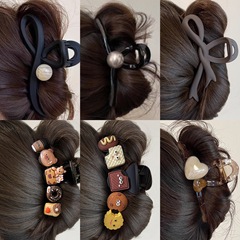 黒のつや消しサメのクリップの大きいサイズのヘアピンの女性の後頭部の髪の量が多いです。