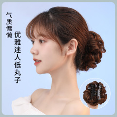 新商品のお団子のかつらの女性はお団子の髪を挟んでかつらを巻いて、ふわふわしているつぼみのかつらを作っています。