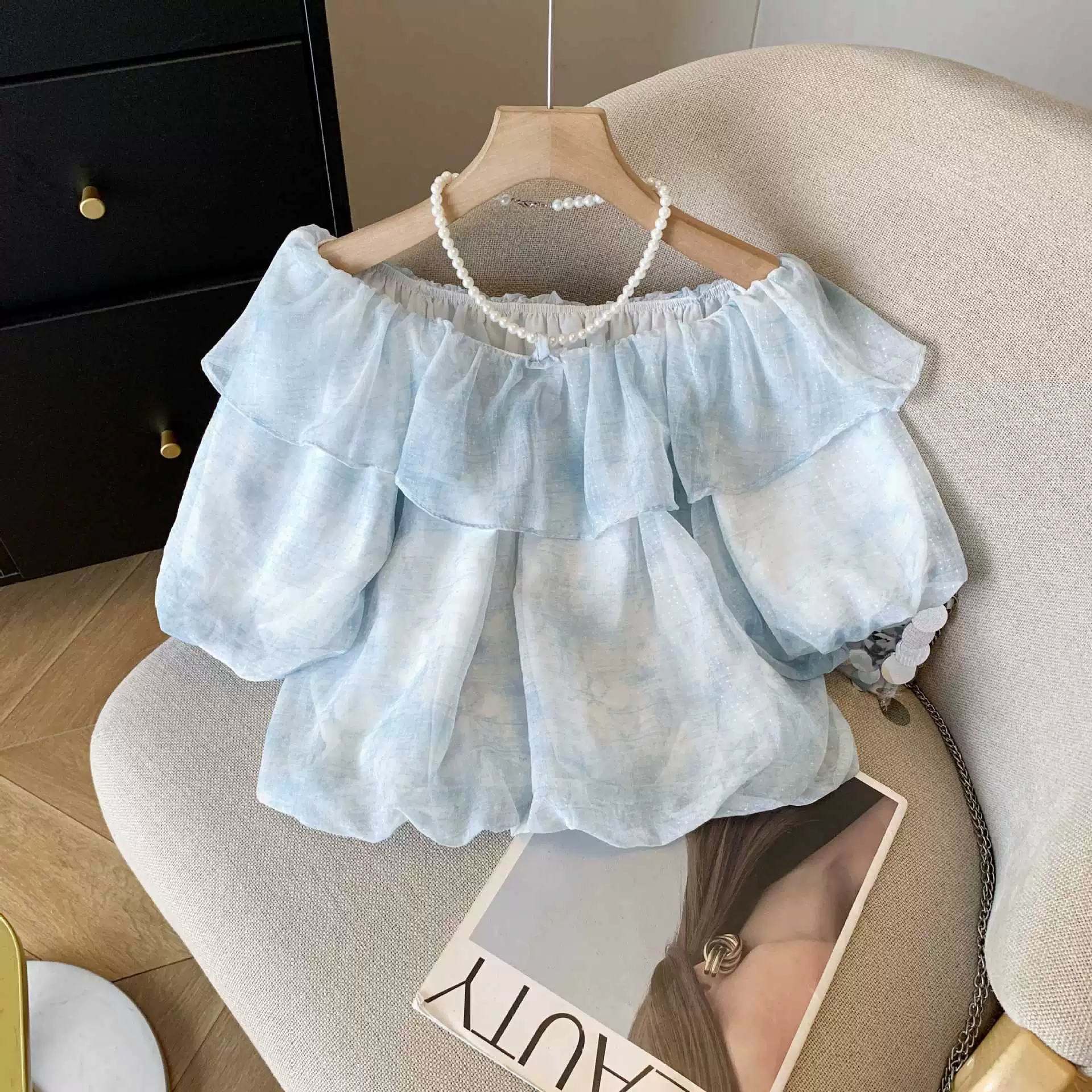 Настоящая фотография французской женской летней стильной шифоновой рубашки с рюшами на одно плечо и красивым топом с цветочным бутоном.