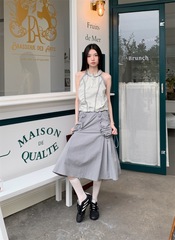 淡いグレーの緑のデザイン感の山系の屋外のタイルのしわは首を掛けて腰のベストの上着の女性を収めます。