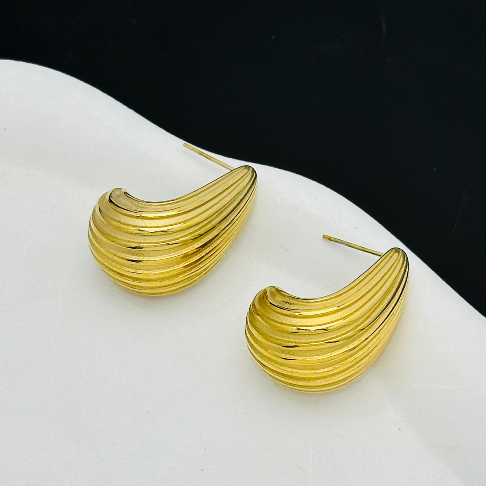 Comercio exterior Europa y Estados Unidos rayas huecas de alta calidad pernos de acero de titanio chapados en oro 18K composto textura pendientes esféricos para mujeres