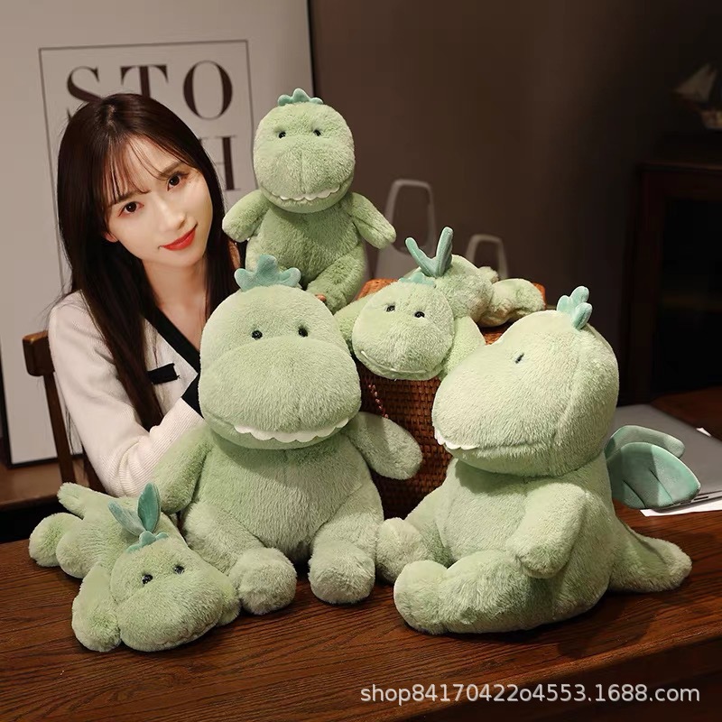 かわいい緑の竜のぬいぐるみのぬいぐるみが腹ばいになっています。子供にプレゼントをプレゼントします。