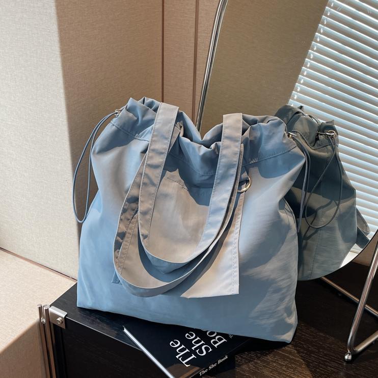 Bolsa de tela de nylon impermeable para mujeres 2025 nuevo tipo bolso de cubo de viaje ligero de gran capacidad bolso de hombro portátil para estudiantes universitarios