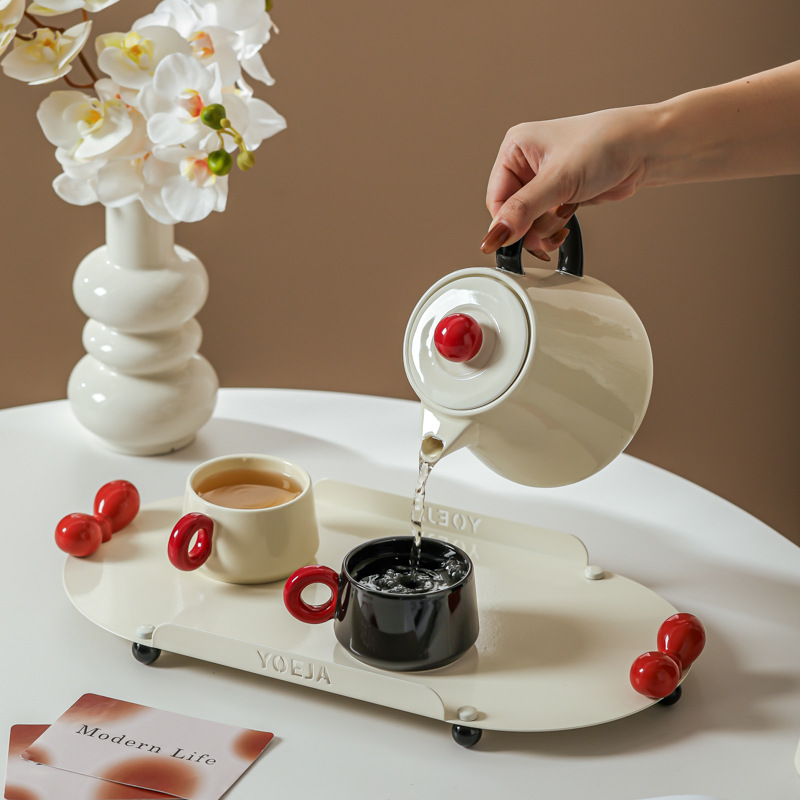 La ama de casa moderna es la misma creativa encantadora de alto valor de la cara con un conjunto de utensilios de agua de cerámica doméstica para invitados con un conjunto completo de tetera de té