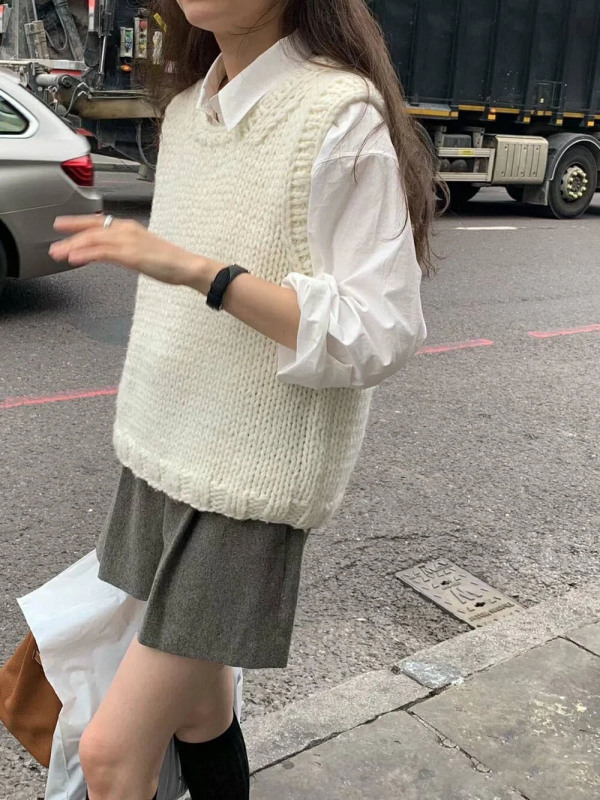 柔らかいモチのレトロな白いニットのベストの女性は秋冬に肩のセーターのベストを重ねて着ます。|undefined