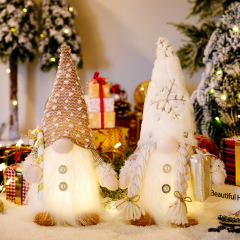クリスマスの新しい装飾品の長いひげのベルベットの帽子は明かりを持ってプレゼントの杖を持っています。