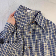 ジェーンさんの青い格子のシャツの中に女性服を重ねてシャツを着ます。