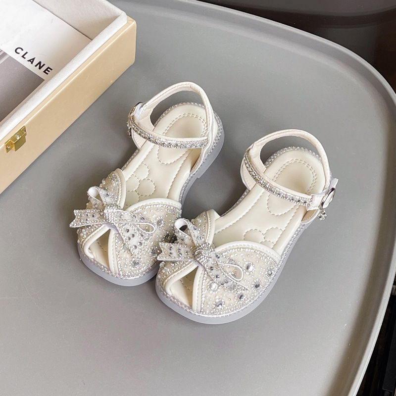 Sandalias Baotou para niñas 2025 verano nuevo estilo bowknot moda cristal princesa zapatos de playa para niños de suela suave marea
