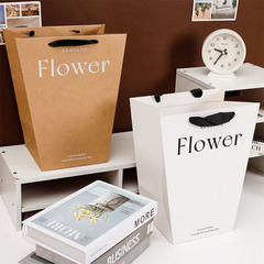台形の花束の手提げ袋の花の芸の生け花の手は袋の花の贈り物の袋を持っています。
