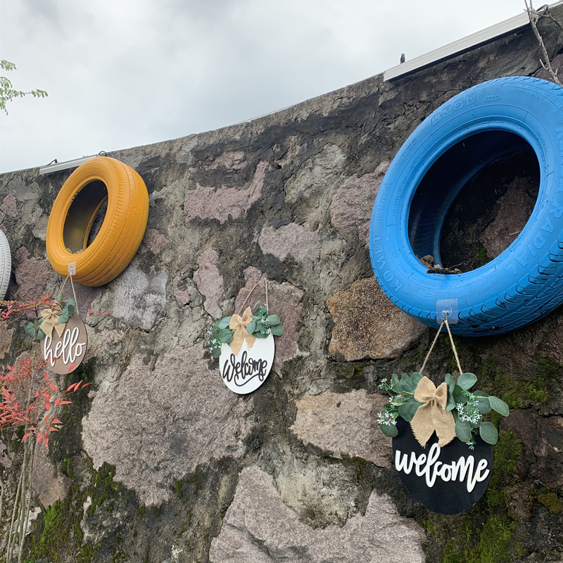 Olá estilo rural. A decoração circular inacabada da porta da frente recebe etiquetas e placas de madeira penduradas_voghion.com