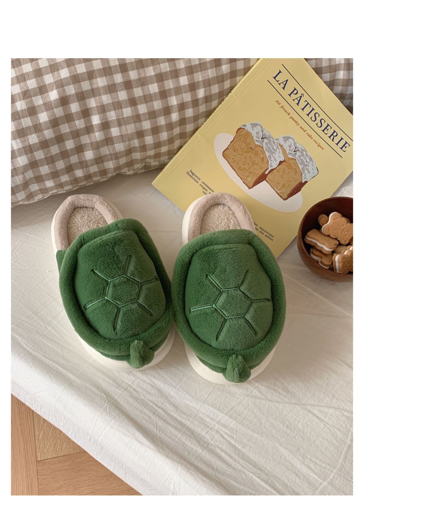 Green turtle-shaped slippers on a light surface with a book in the background.