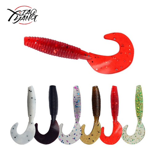 Factory-supplied bulk soft lures—curly-tail grubs for lure fishing, lead-head hooks, Texas rig setups, and salt-infused, fishy-smelling soft worms.