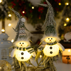 国境を越えて人気のあるクリスマスの雰囲気は冬の雪だるまを飾ってクリスマスの緑のニット帽にランプ付き人形を飾る