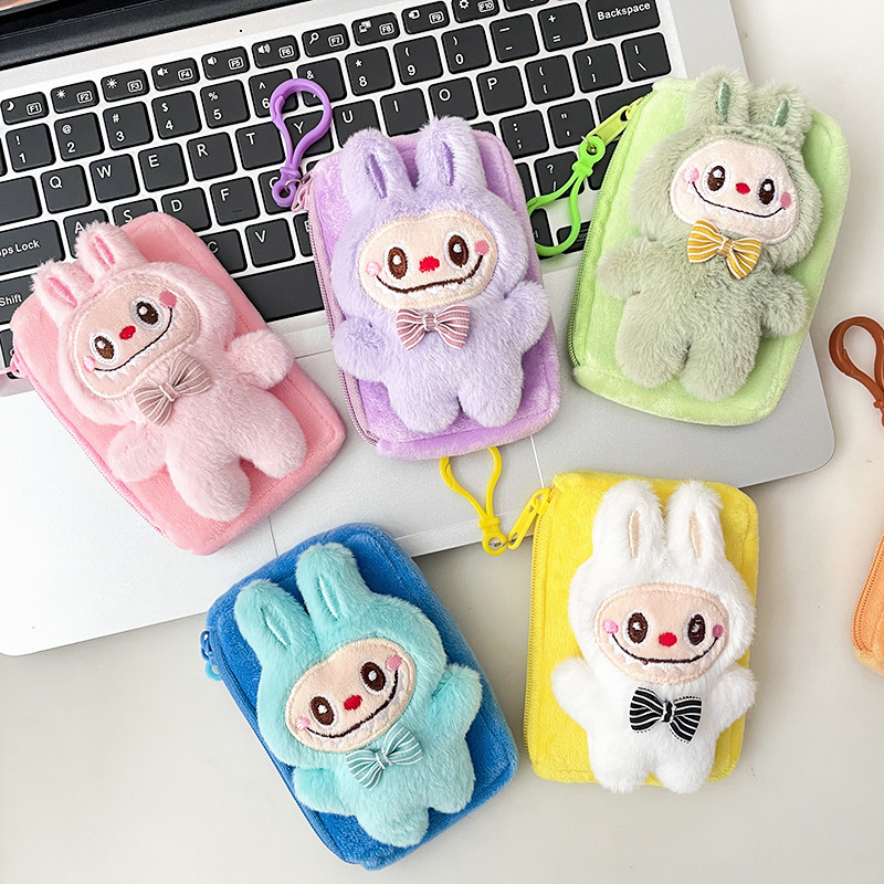 震え音の赤い本が爆発してかわいいぬいぐるみの布の小銭入れのキーホルダーのイヤホンのかばんにプレゼントを掛けます。|undefined