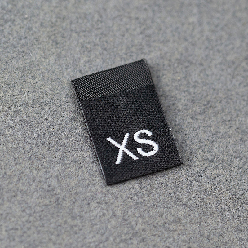 En stock Etiqueta de tamaño de alta densidad en blanco y negro Etiqueta de tamaño universal Etiqueta de código de letra inglesa Pantalones Etiqueta de código de cuello de camiseta