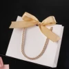 White bag, golden handheld hair band