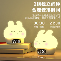 カラフルな雰囲気の恥ずかしがり屋のウサギは夜の明かりをたたいて目覚まし時計の寝室のベッドの上で乳をあげます。