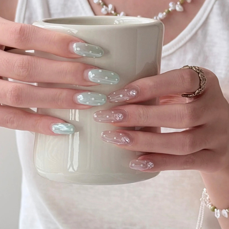 Handmade press-on nails in mint green and light pink with clear polka dots, fresh and gentle oval shape, suitable for daily use and removable
