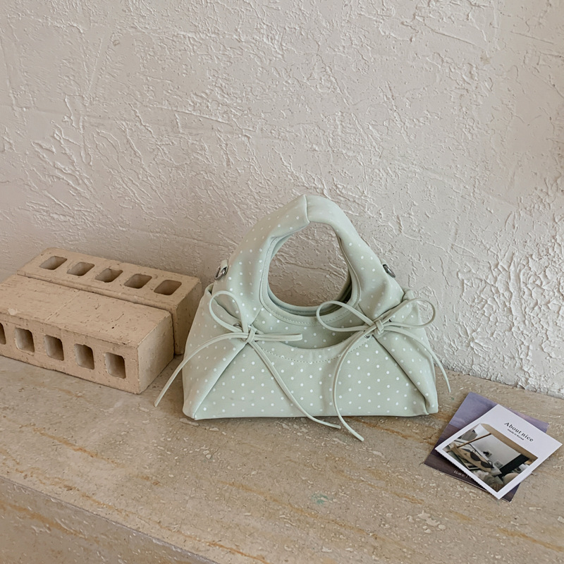 Bolsa de mano de arco exquisita coreana para mujeres verano 2026 simple diaria versátil onda punto sensación de hombro mochila
