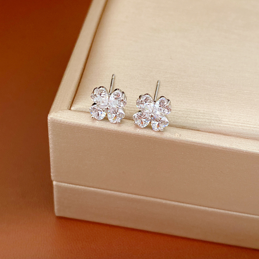 Agujas de plata zircon flores de hierba afortunada simple estilo de viaje versátil pendientes ligeros de lujo alta sensación de auriculares al por mayor