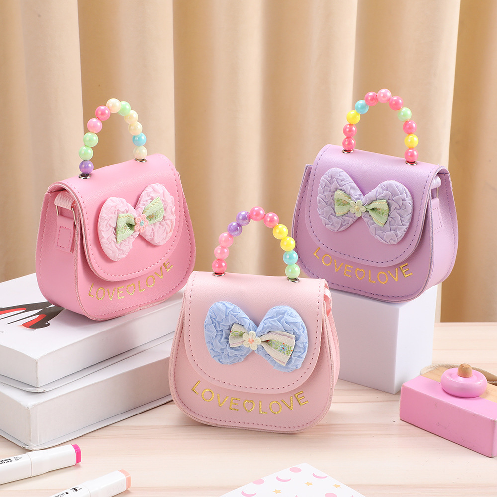 Bolso de cambio para niños lindos bolsos de hombro chicas perlas bolsos portátiles bolsos de arco al por mayor almacenamiento infantil lindos