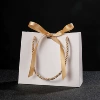 White bag, golden handheld hair band