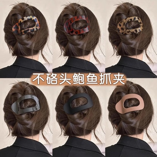 Shellfish-shaped hair clip with a round, flat back, designed to clip onto a woman's full, rounded hair bun, featuring an arched tail hair clip as a head accessory.