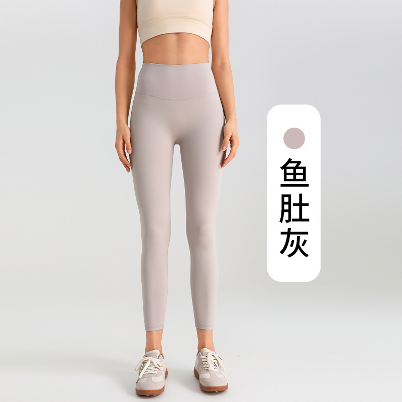 ヨガのズボンの女性は腹を収めて尻を持ちます。|undefined