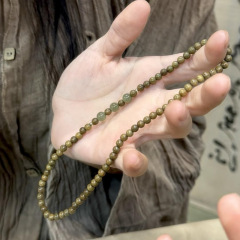 二重に木の玉のブレスレットをかぶっています。