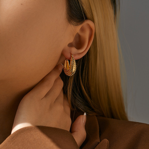 Elegant, heavyweight-inspired ear clips with a textured, premium feel—featuring a retro-style oval copper tube design plated in 18K real gold and boasting a distinct granular texture.