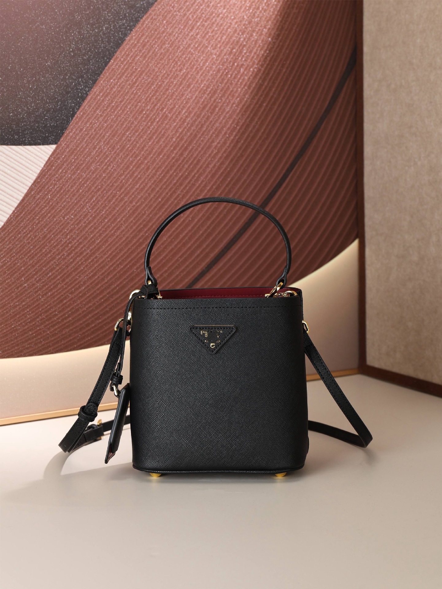 Cross-border P-brand triangular logo bucket bag, featuring a crosshatch pattern, made of cowhide leather, can be carried by hand, worn as a shoulder bag, or as a crossbody bag, designed for women