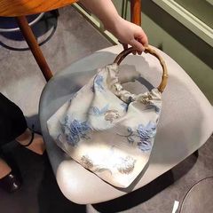 A unique and original French vintage bamboo-tipped hand-held bag with elegant gold thread embossed floral patterns, exuding luxury and sophistication.