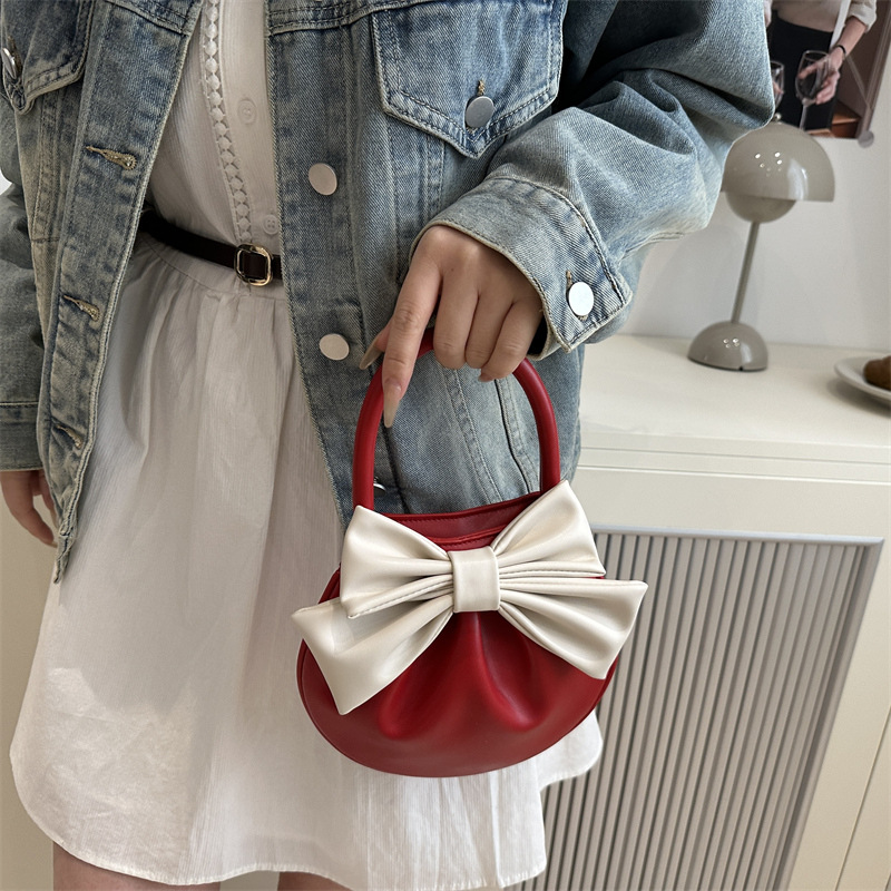 2025 primavera y verano nuevo nicho de diseño de arco bolsos portátiles de mujer alta sensación pequeña bolsa redonda roja