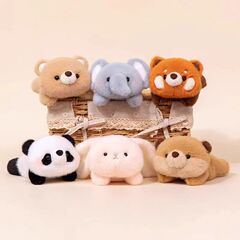 かわいい手のひらの中の赤ちゃんのぬいぐるみのぬいぐるみの赤ちゃんの腹ばいになっている赤ちゃんの赤ちゃんの腹ばいになっている赤ちゃんのアライグマの人形のテーブルの置物が勉強に付き添う