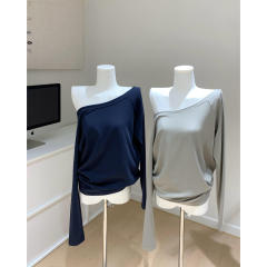 肩を斜めに引いて肩を露出するtシャツ女性の春のゆるい肩の長袖はやせているニットの上着を見せます。