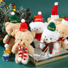 クリスマスのかわいいぬいぐるみのヒグマがケーキを焼いて帽子のマフラーを飾ったベアーの平安夜の衣装を飾った