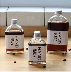 現物卸売りの斜め肩の飲み物の瓶のアーチ形の平瓶のジュースのコーヒーの瓶の小さい酒の瓶の新型のテイクアウトミルクティーのガラス瓶