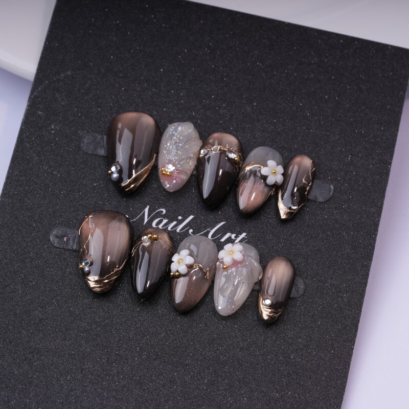 Gentle brown gradient with smudged almond-shaped press-on nails, handcrafted with three-dimensional small white flowers and metallic rhinestones, offering a light luxury look that enhances skin tone for everyday wear Gentle brown gradient with smudged almond-shaped press-on nails, handcrafted with three-dimensional small white flowers and metallic rhinestones, offering a light luxury look that enhances skin tone for everyday wear