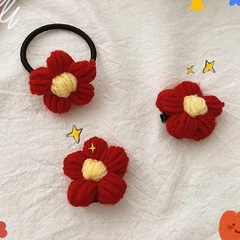 A handmade wool hook-knitted red flower hairpin with a small student award, given to a kindergarten teacher.