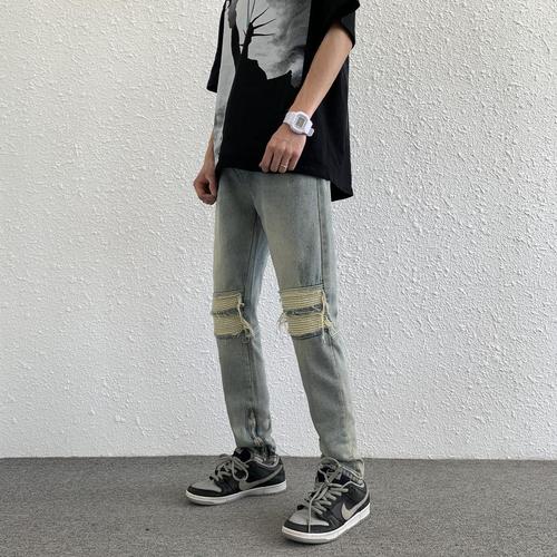 Euro-American trendy high-street light-blue distressed denim jeans for men: vintage-style, slim-fit, tapered legs, with zip-up cuffs—versatile and easy-to-match trousers