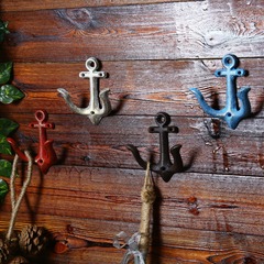 レトロな鉄の錨のフックの粗い砂利の質感の鉄芸の装飾品の壁は喫茶店のショーウインドーを飾って道具を撮影します。