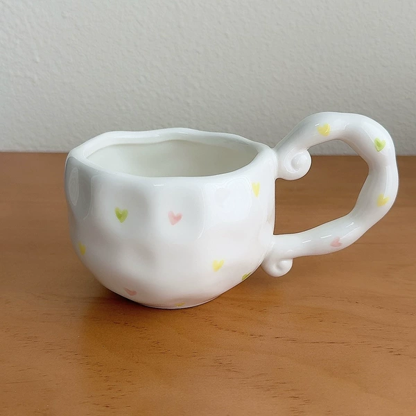 Irregular handle cup with small heart pattern on white background
