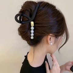 髪の量が多いです。大きいサイズのヘアピンを挟んでいます。女性の後頭部に髪を巻いています。